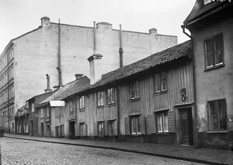 Styrmansgatan 32 och 34 norrut mot Storgatan. Utanför porten till Styrmansgatan 32 står en grupp pojkar och vid fönstret en trappa upp sitter en skvallerspegel.