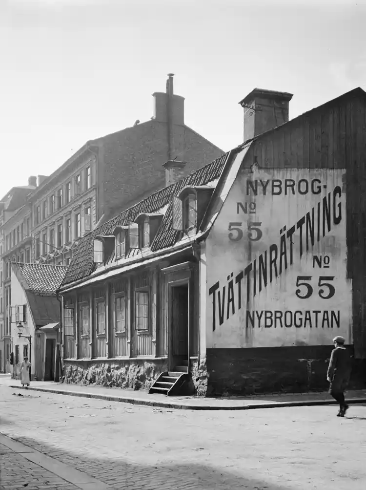 Nybrogatan söderut från Östermalmsgatan. Nybrogatan 55 (nu 75), Hellerströmska tvättinrättningen. En pojke går förbi skylten på gaveln.