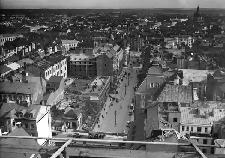 Vy från södra Kungstornet längs Kungsgatan, mot Stureplan. I förgrunden häst och vagn på Regeringsgatan. Barn leker på skolgård som ligger på taket på en byggnad.